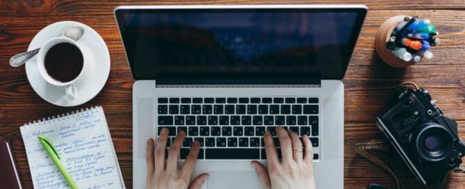 Developer making updates to website with camera sitting next to laptop