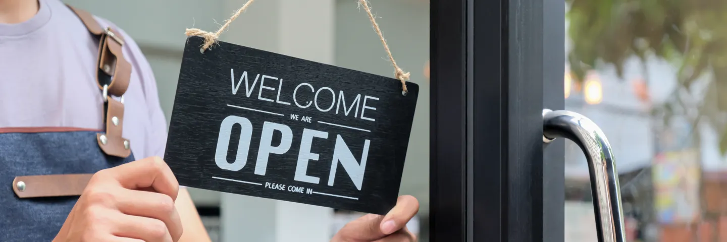 cropped-shot-of-business-owners-hold-an-open-sign-RV6URXV Woman business owner turning 'Business Open' sign on door