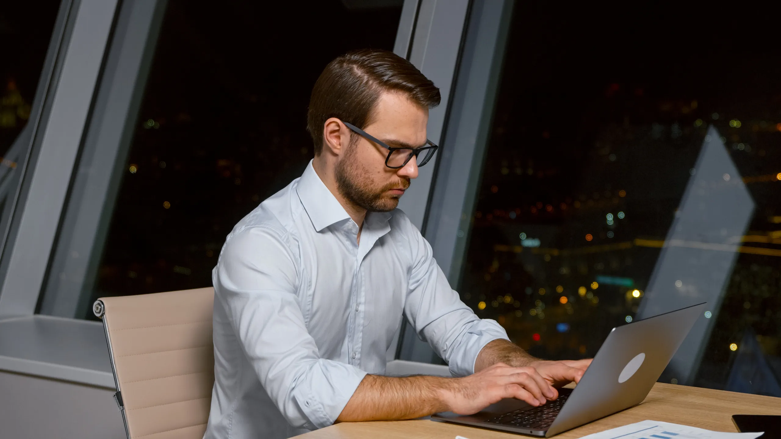 Smiling businessman typing on computer in office at night business man working on laptop