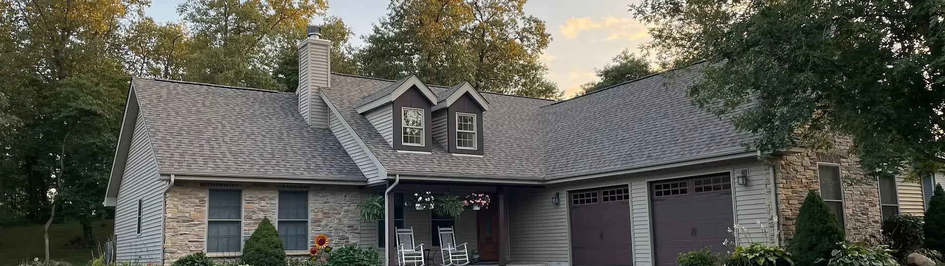 Two-story stone and siding home with a new gray shingle roof and two-car garage
